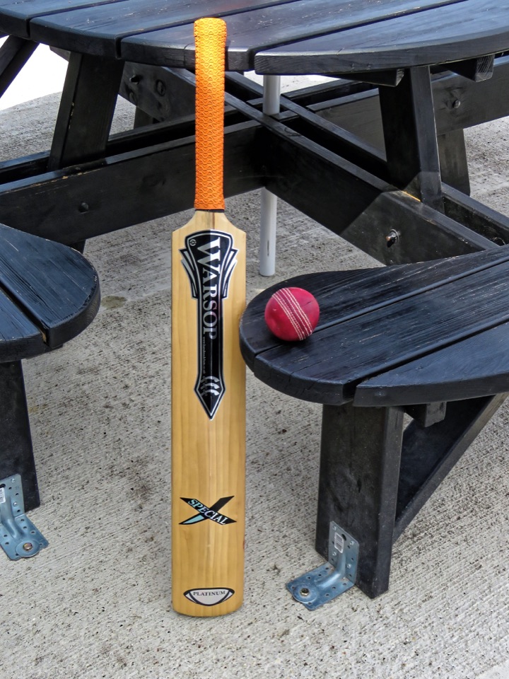 Cricket bat and red ball beside a bench at Bishop’s Stortford Cricket Club